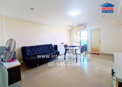 Spacious and well-lit living room with a comfortable blue sofa and dining area