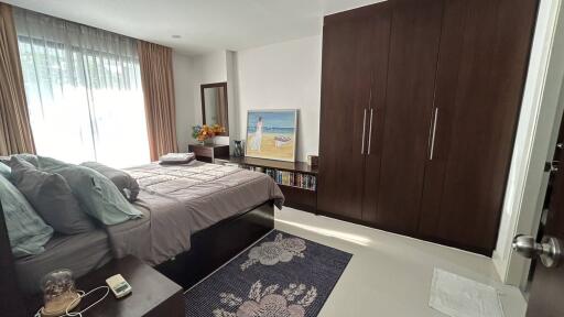Spacious and well-lit bedroom with large bed and wooden wardrobe