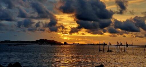 Scenic sunset over the ocean with cloudscape and distant hills