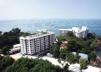 Aerial view of coastal apartment buildings surrounded by lush greenery and ocean views