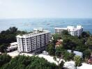 Aerial view of coastal apartment buildings surrounded by lush greenery and ocean views