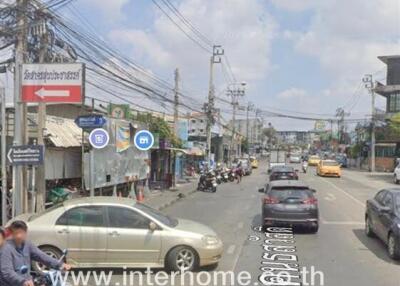 Busy urban street with various vehicles and commercial shops