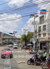 Busy street scene outside a real estate building with visible signage and multiple vehicles