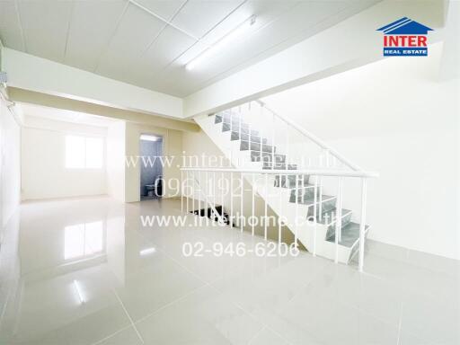 Spacious and bright living room with sleek white tiles and modern staircase