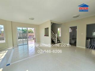 Spacious and well-lit living room with staircase and multiple entryways