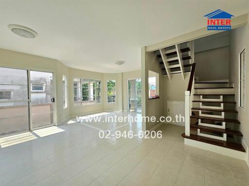 Spacious living room with staircase and ample natural light