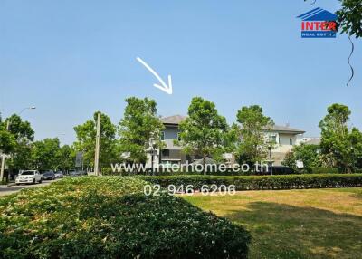 Exterior view of a spacious two-story house with lush greenery and clear blue skies