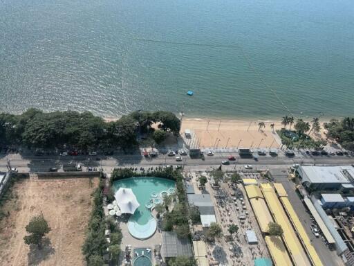 Aerial view of coastal real estate with leisure amenities next to a sandy beach
