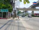 Exterior street view near residential property showing roadway, pedestrian path, and nearby elevated train track