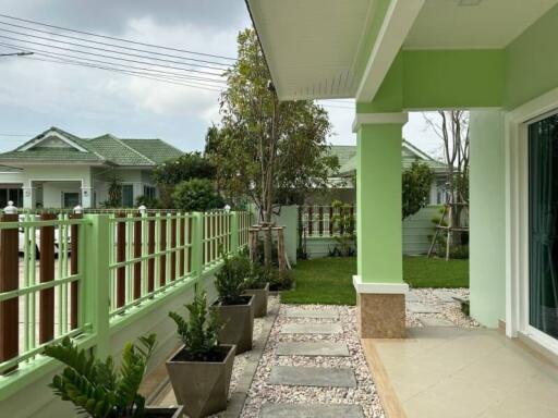 Spacious patio with green railings and a view to a serene garden