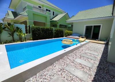 Spacious outdoor pool with stone walkway and lush green surroundings