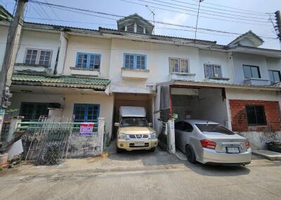 Exterior view of a multi-unit residential building with parked cars