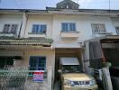 Exterior view of a residential townhouse with parking space and a vehicle parked underneath