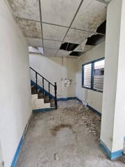 Interior of a dilapidated building with damaged ceiling and debris on floor