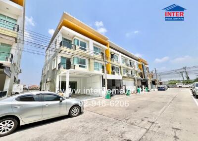 Exterior view of modern townhouses with parked cars under a sunny sky