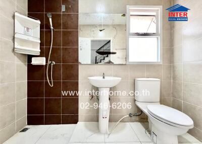 Modern bathroom with neutral tiles, essential fixtures, and window for natural light