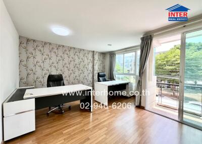 Bright and spacious bedroom with wooden flooring, luxury furniture including a desk and a comfortable chair, large windows with a view