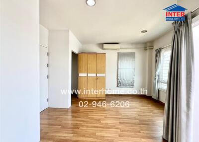 Bright and spacious bedroom with wooden flooring, large window, and built-in wardrobe