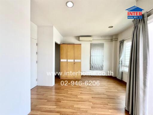 Bright and spacious bedroom with wooden flooring, large window, and built-in wardrobe