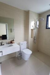Modern bathroom with wall-mounted sink, toilet, and large shower