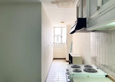 Compact kitchen with white tiles and natural light