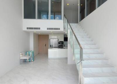 Modern spacious building interior with open floor plan featuring elegant staircase and kitchen in the background