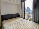 Urban bedroom with large window offering cityscape views