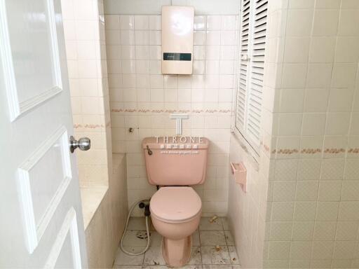 Small beige bathroom with toilet and paper towel dispenser
