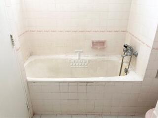 Spacious white tiled bathroom featuring a bathtub and modern fixtures