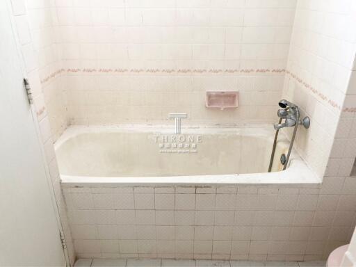 Spacious white tiled bathroom featuring a bathtub and modern fixtures