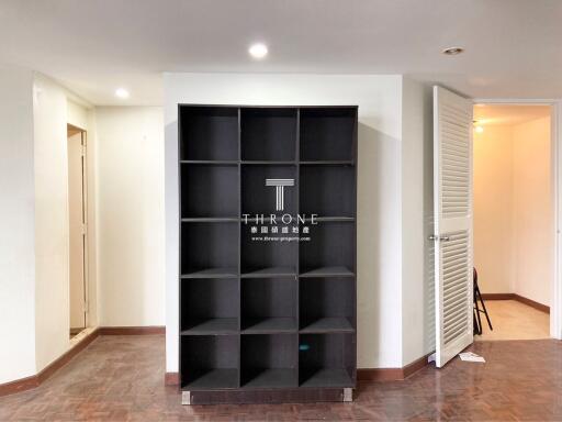 Spacious living room with large shelving unit and wooden flooring