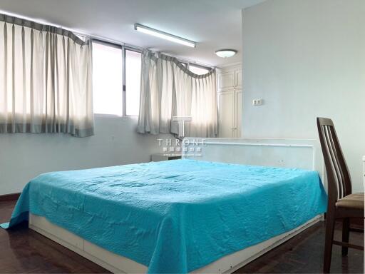 Bright and spacious bedroom with large windows and blue bedding