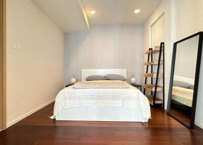 Modern bedroom with ensuite bathroom, wooden flooring, and large mirror