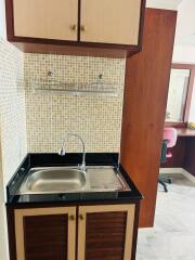 Compact kitchenette with stainless steel sink and wooden cabinetry