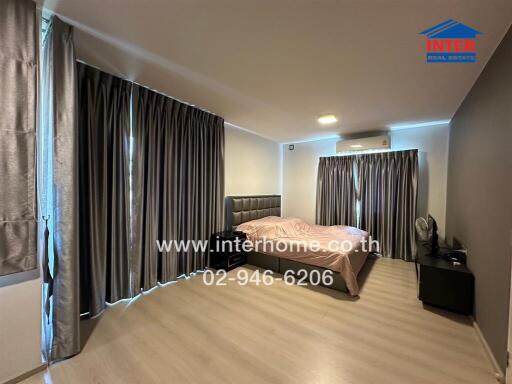 Spacious modern bedroom with large bed and extensive curtains