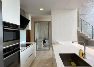 Modern kitchen with integrated appliances and staircase leading to upper floor