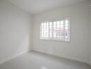Bright and empty bedroom with large window and white walls