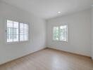 Spacious empty bedroom with large windows and hardwood floors