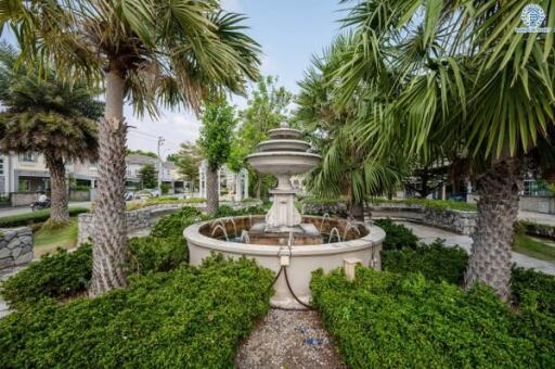 Elegant garden in a residential area with a central fountain surrounded by lush greenery and palm trees