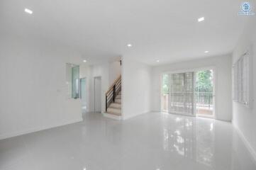 Spacious living room with natural light and modern staircase