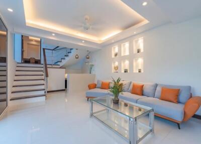 Modern living room with white and orange decor and staircase