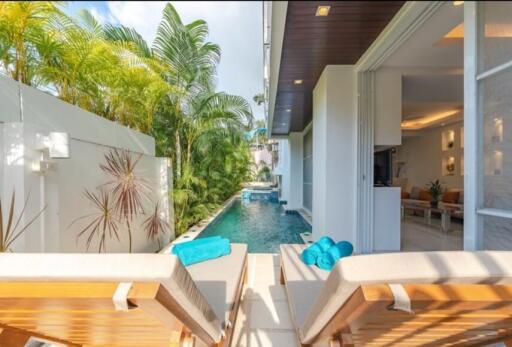 Luxurious outdoor swimming pool area with lounge chairs and lush greenery