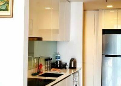 Compact and well-equipped modern kitchen with refrigerator and white cabinetry