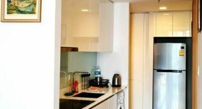 Compact and well-equipped modern kitchen with refrigerator and white cabinetry