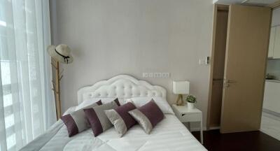 Elegant bedroom with a white double bed and decorative purple pillows