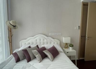 Elegant bedroom with a white double bed and decorative purple pillows