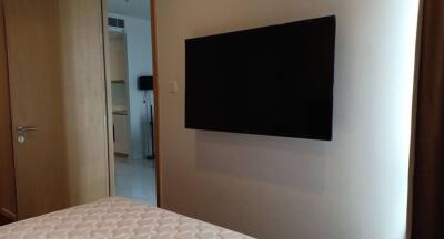 Modern bedroom with wall-mounted TV and entrance to hallway