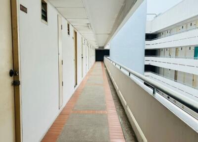 Long corridor in a residential apartment building with multiple doors and balcony railings