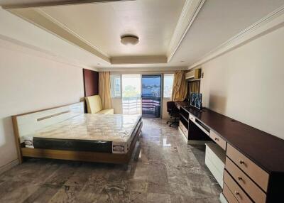 Spacious bedroom with large bed, study desk, and balcony access