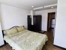 Spacious bedroom with well-made double bed, wardrobe, and access to another room